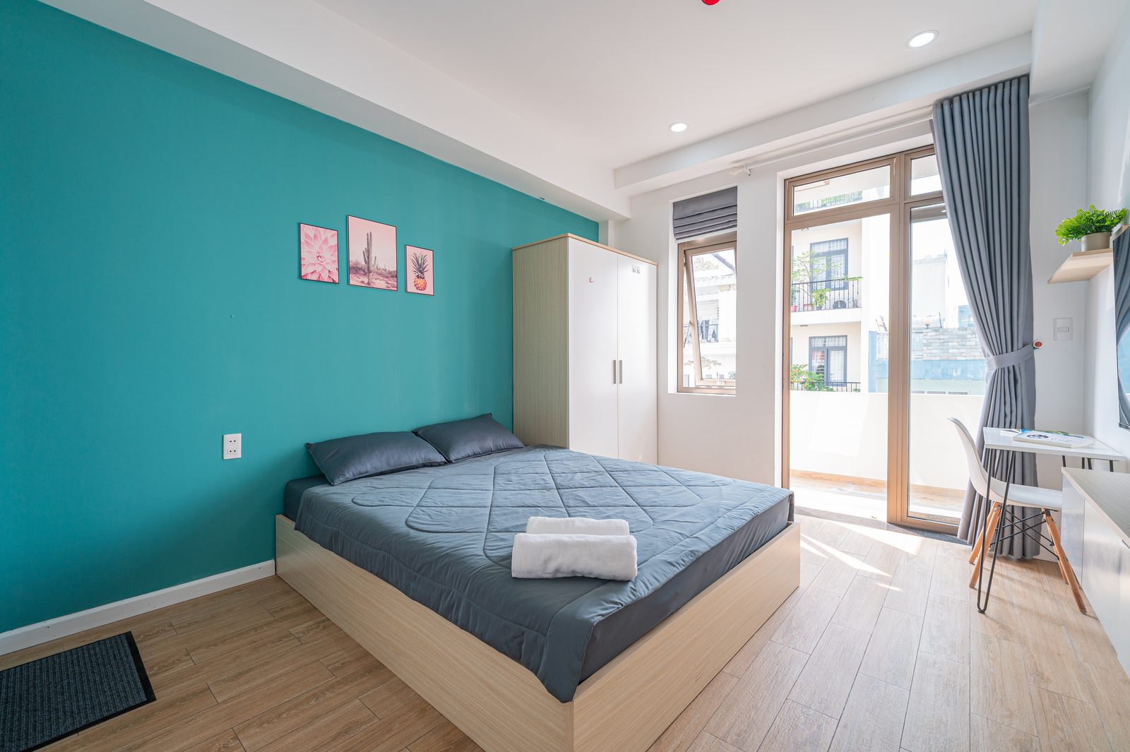 Studio 3.2 interior with queen bed, teal accent wall and balcony windows
