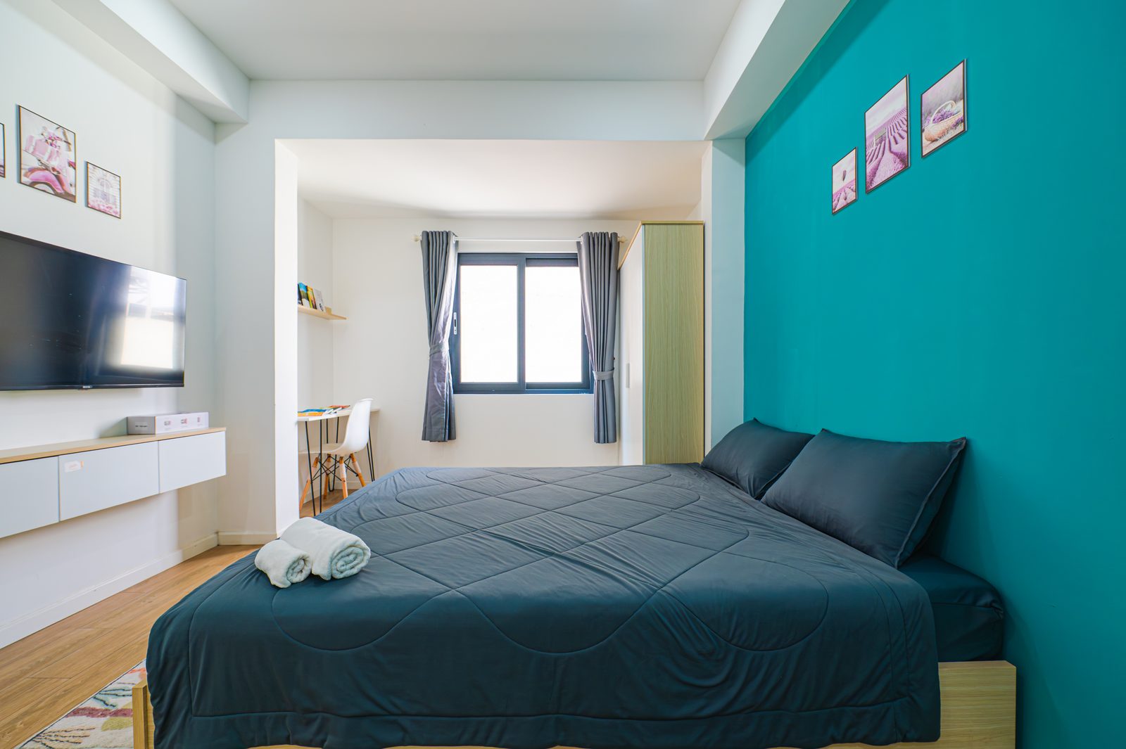 Studio 4.5 interior with queen bed, teal accent wall and bright windows