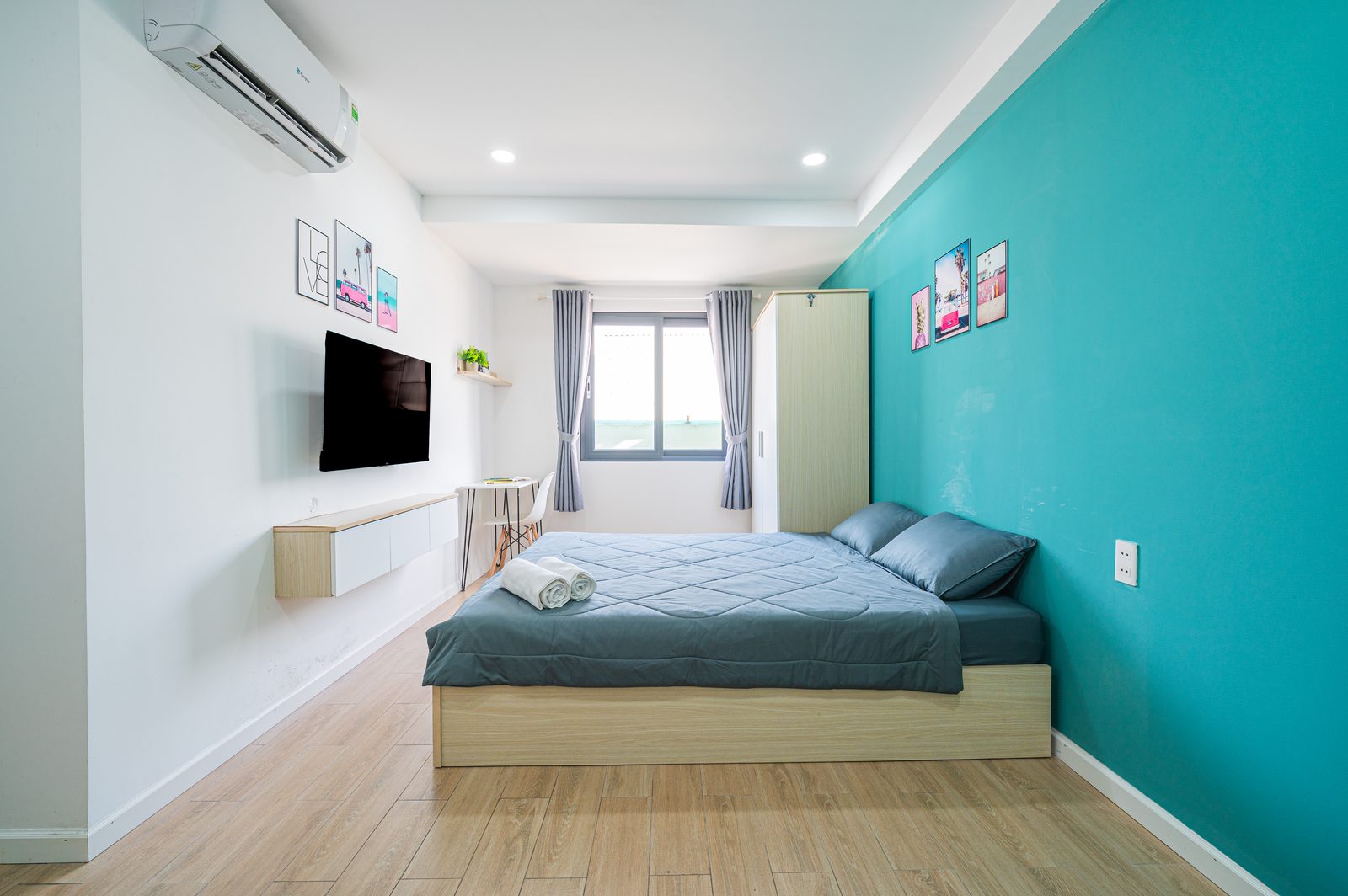 Studio 5.4 interior with queen bed, kitchenette and teal accent wall